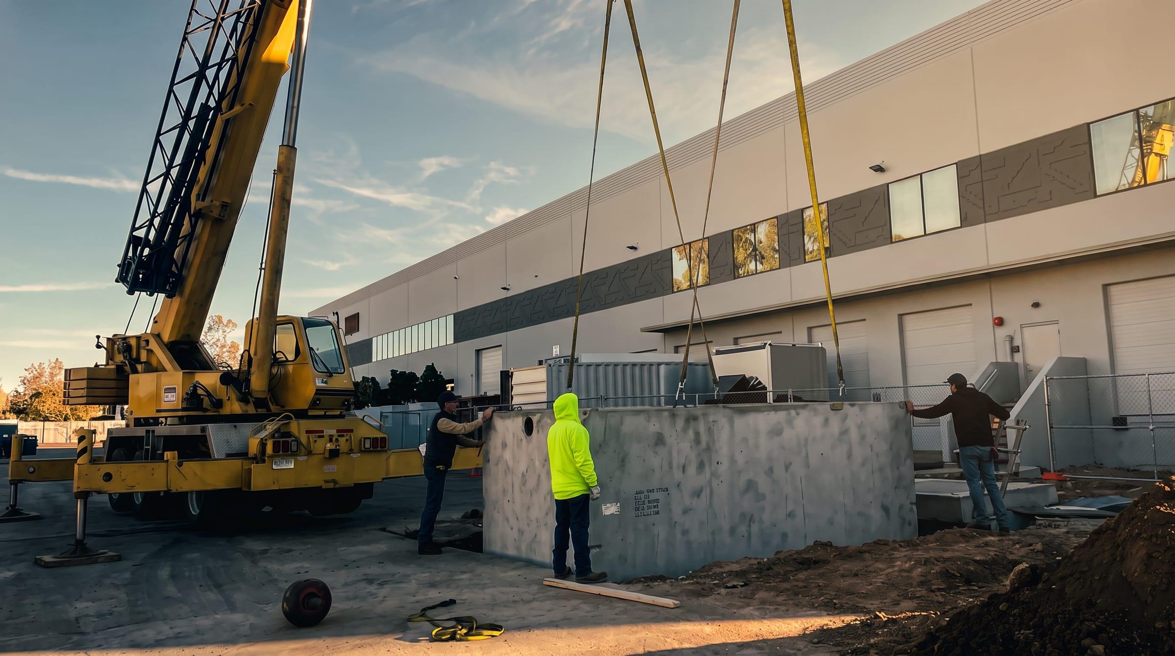 Crane lowering a precast vault at golden hour
