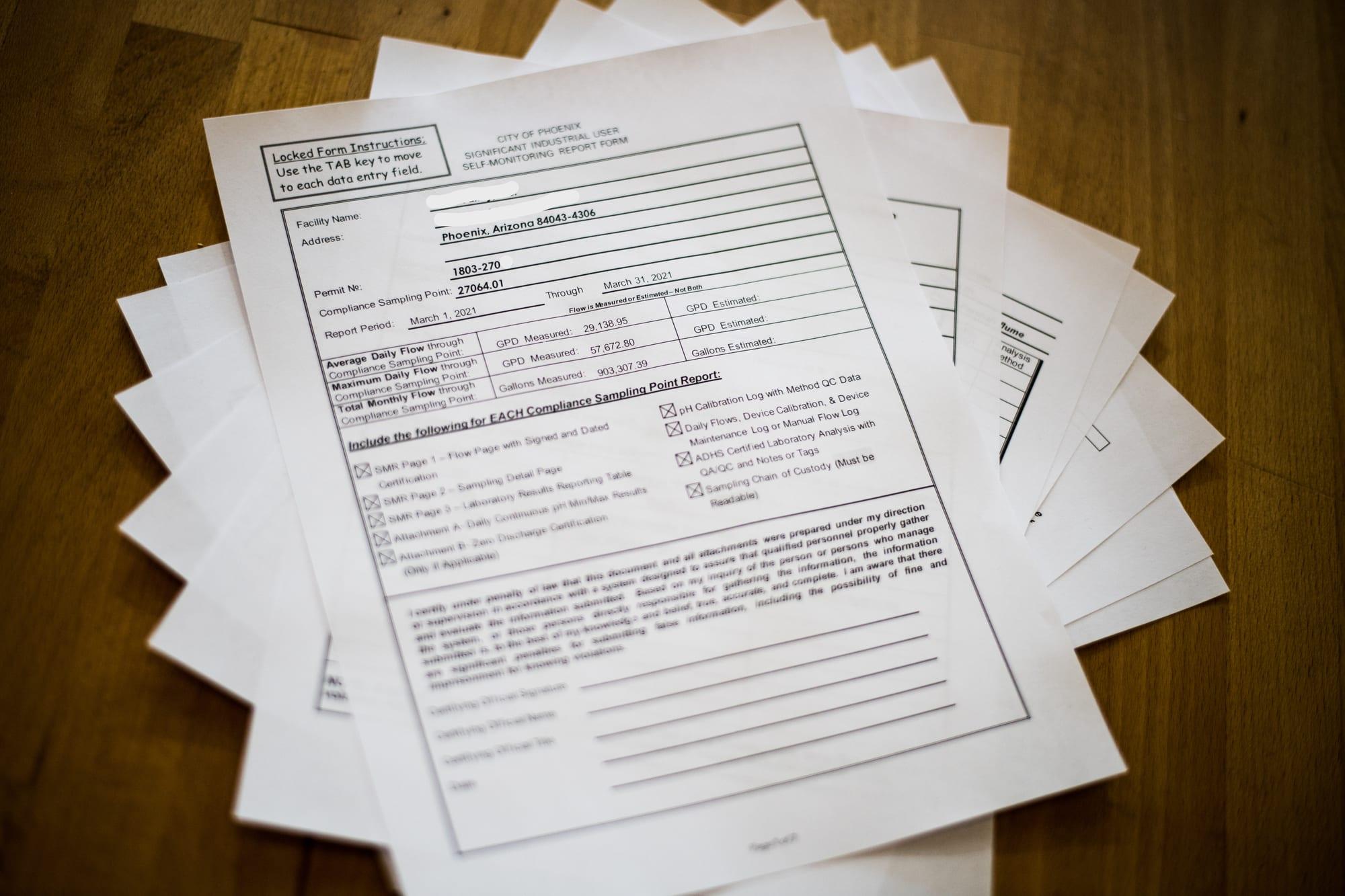 A completed self monitoring report packet fanned out on a desk
