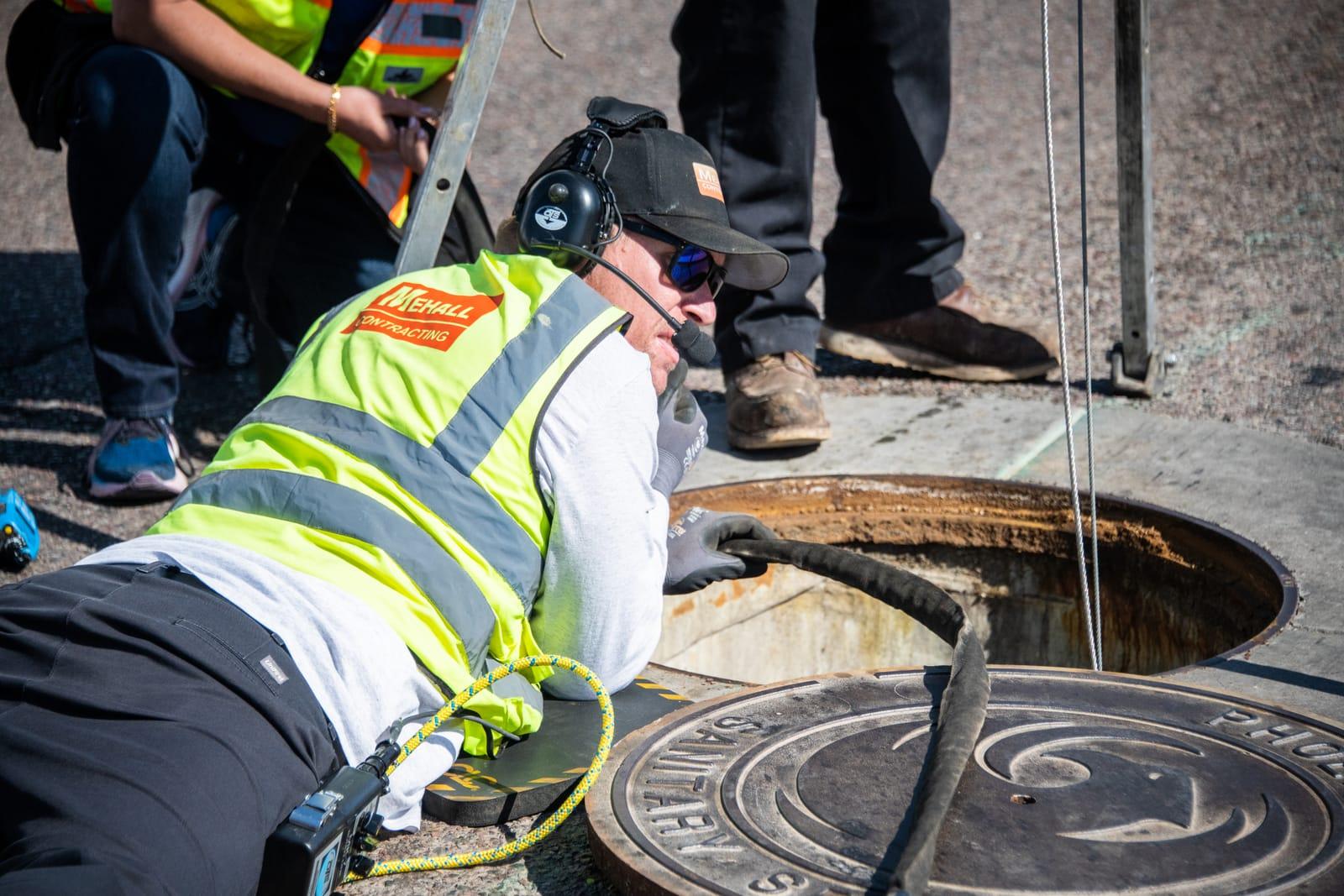 Comms operator with a headset at the manhole edge