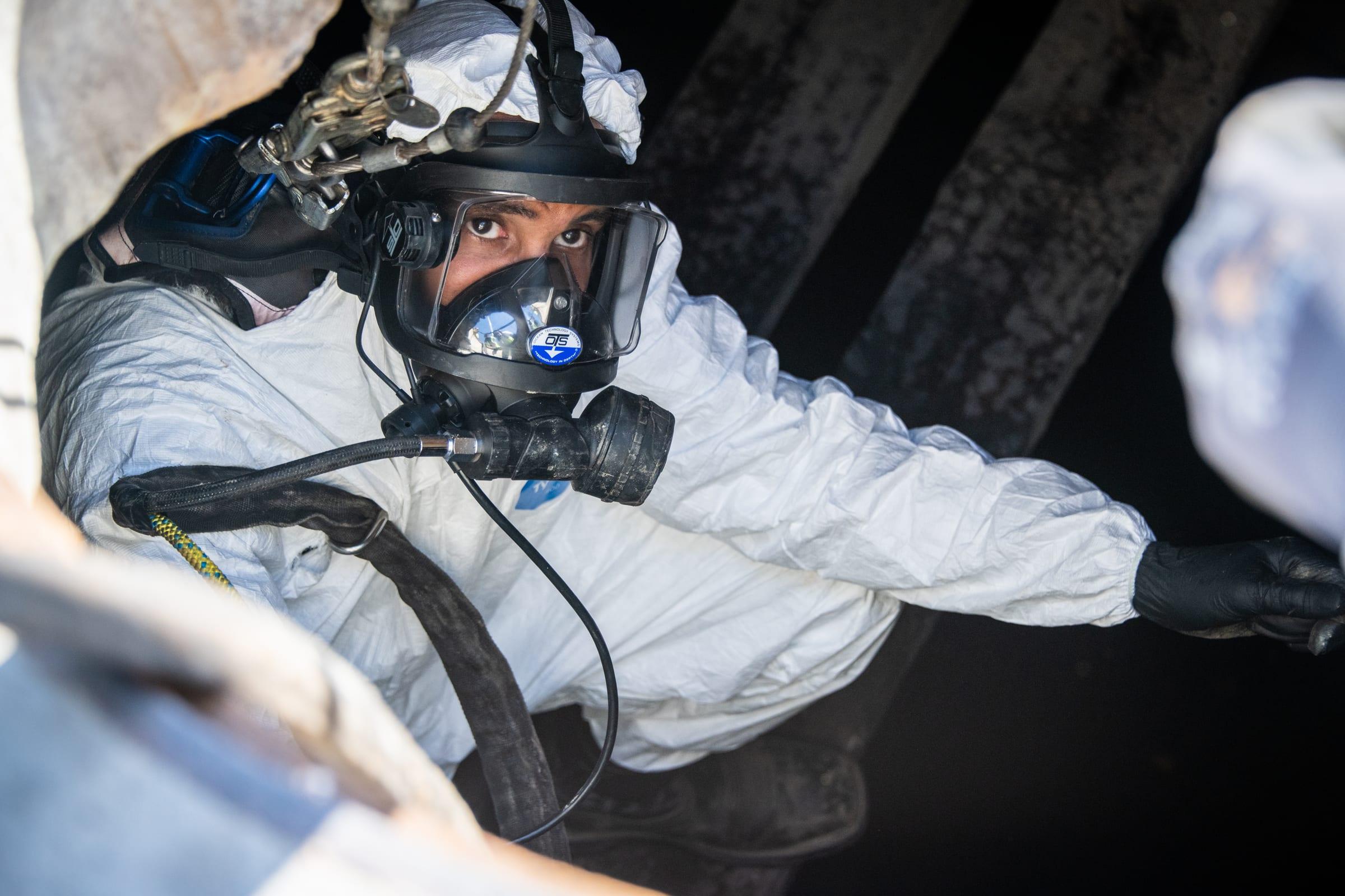 Technician in a supplied air mask inside a confined space