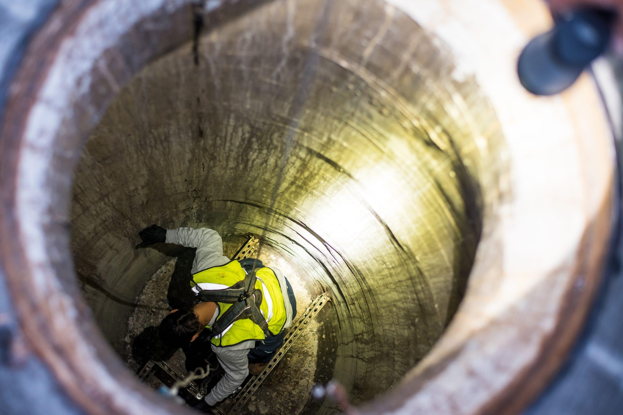 Technician descending into a deep wet well